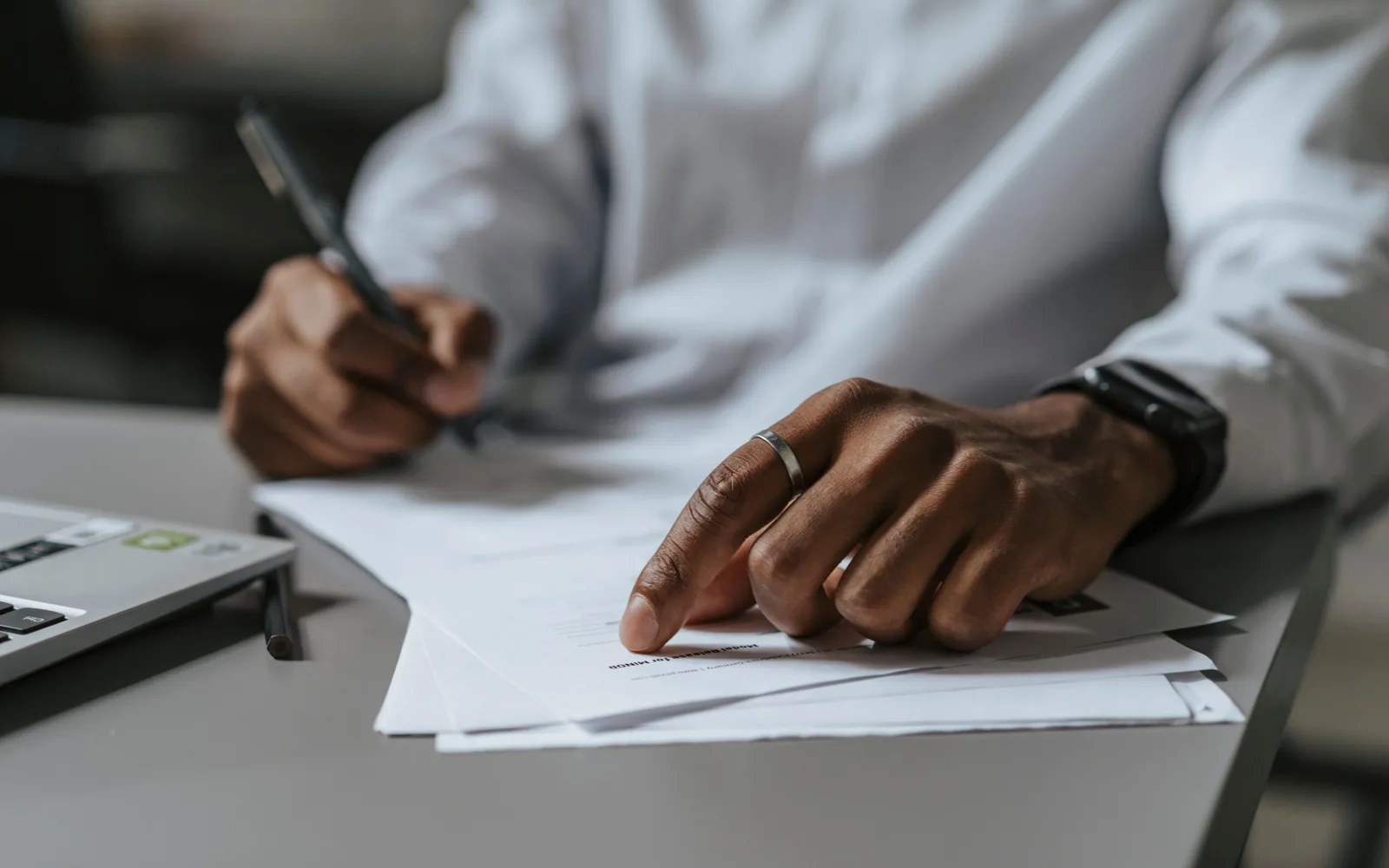 Une personne vérifie des informations professionnelles sur des documents et un ordinateur portable